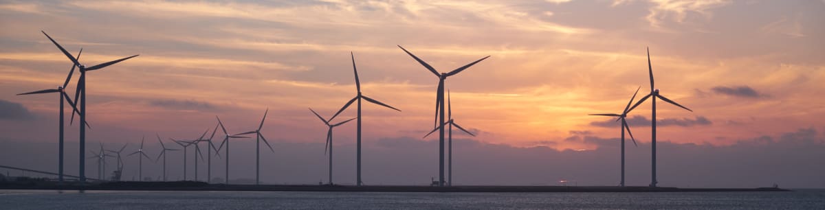 Wind turbines in the sea with a sunset background